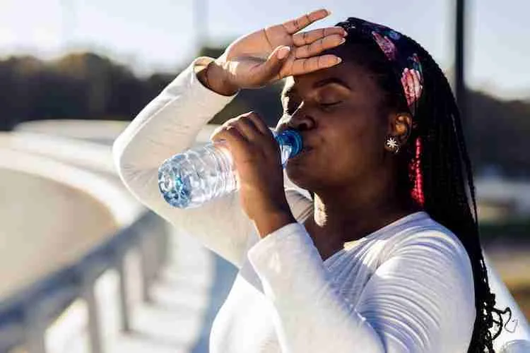 Young plus size women resting after running drinking water.